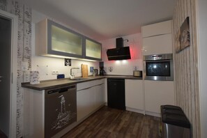 A compact kitchen with a dishwasher, a built-in oven, and a microwave. - NEW! Villa Totti - Lucas Stube (Neßmersiel)