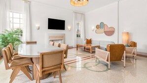 Ein modernes Wohnzimmer mit einem runden Esstisch, Sofas und einem Fernseher.