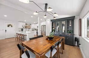 Een moderne keuken met een houten eettafel, barstoelen en een hanglamp.