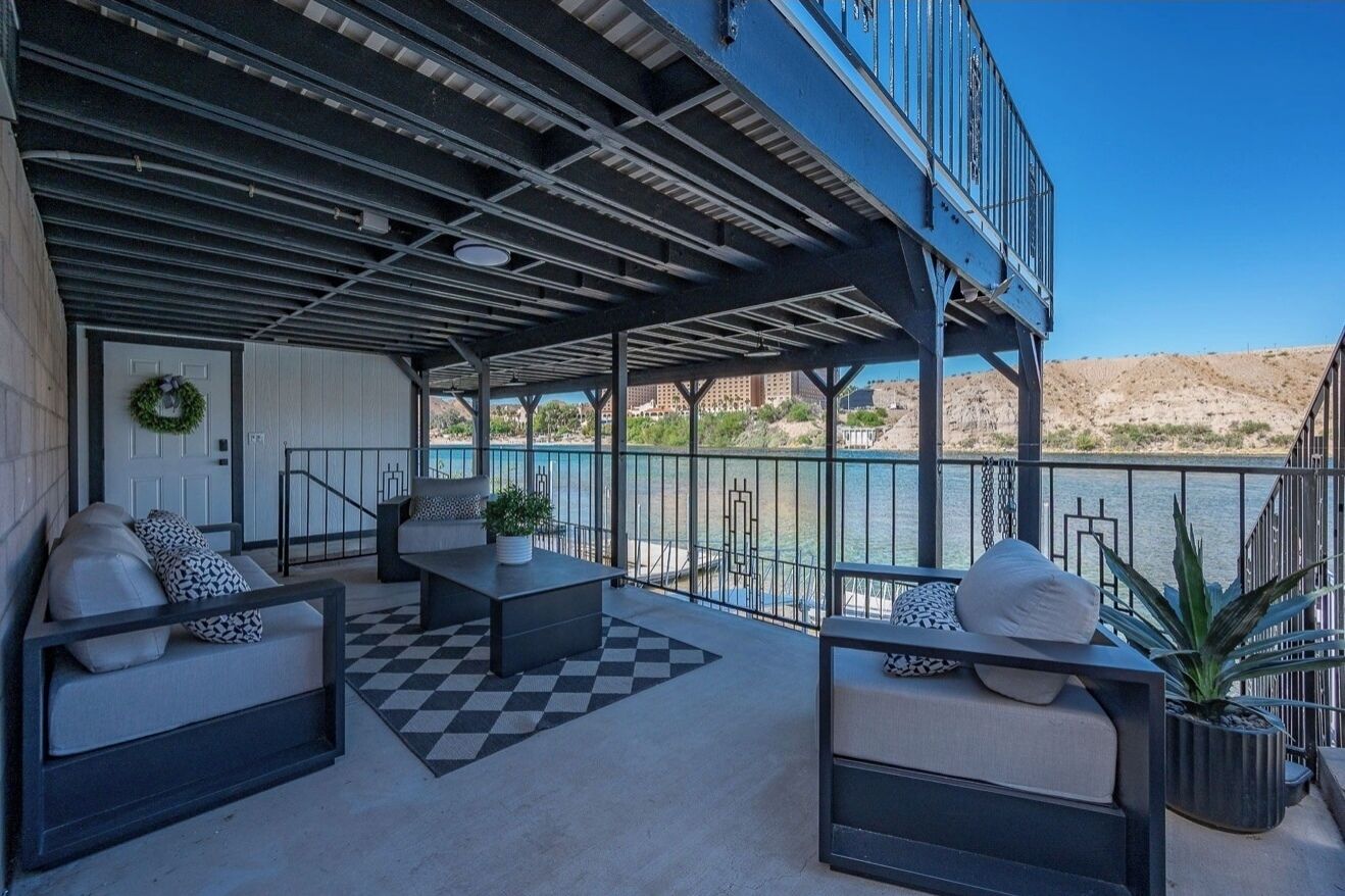 A covered outdoor seating area with a checkered floor, a potted plant, and a view of a body of water.