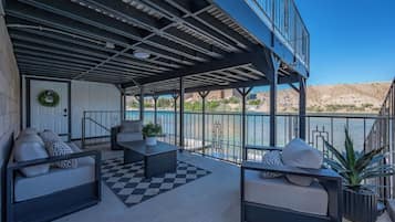 A covered outdoor seating area with a checkered floor, a potted plant, and a view of a body of water.
