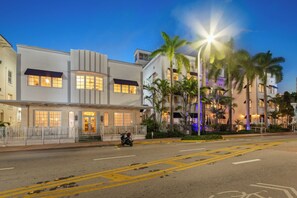 A hotel with a modern facade, multiple balconies, and a street view with palm trees.