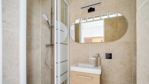 Ein Badezimmer mit Dusche, Waschbecken, Spiegel und Handtuchhalter.