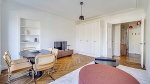 Ein modernes Wohnzimmer mit Esstisch, Stühlen, einer Couch, einem Fernseher und einem Kleiderschrank.