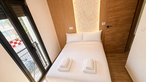 A neatly made bed with white linens and two folded towels, a wooden floor, and a view through a glass door to the outside. - Collection Las Ventas Apartamento G Cerca de la Plaza de Toros (Madrid)