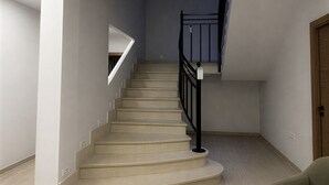 A staircase with a handrail, a light-colored floor, and a green sofa in a room with white walls. - Collection Las Ventas Apartamento G Cerca de la Plaza de Toros (Madrid)