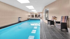 A swimming pool with a sunroof, a seating area with chairs, and a view of the outside. - Spacious villa with private pool, 5 bedrooms and 5 bathrooms (Rogaland)
