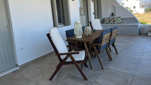 Eine überdachte Terrasse mit Holztisch und -stühlen, einer Sitzecke und Blick auf die umliegenden Gebäude.