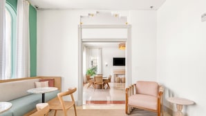 A modern living room with a sofa, chairs, a small table, a dining area with a table and chairs, and a TV. - Aloha Fridays | 2 Queen | Digital Check-In, Lounge, Friday Vibes | 2 Units (Miami Beach)