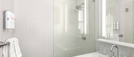 A modern bathroom with a glass-enclosed shower, a white sink with a chrome faucet, and a towel rack with white towels.