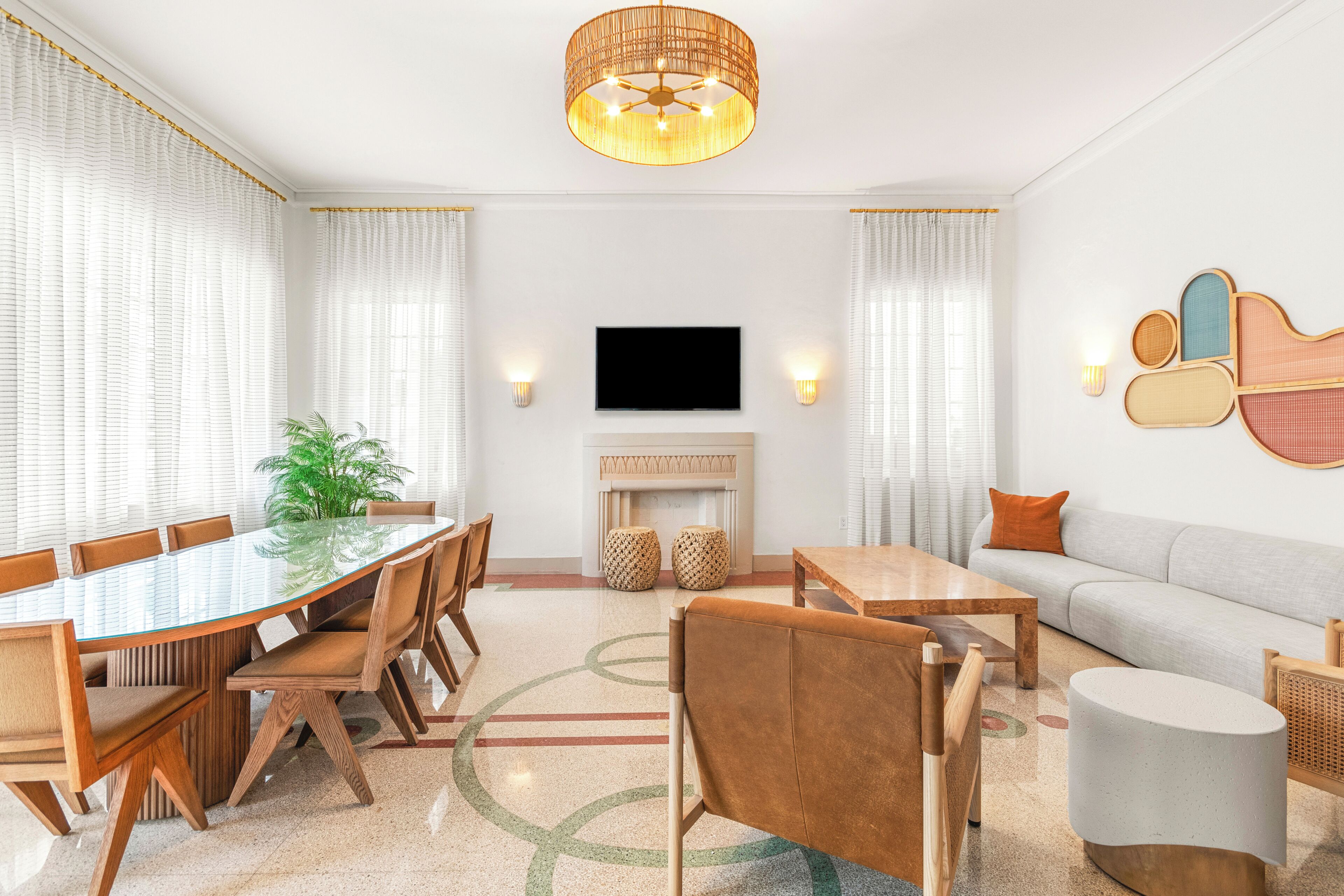 Un salon moderne doté d’une grande table à manger avec un plateau en verre, de canapés, d’un téléviseur à écran plat et d’une cheminée.