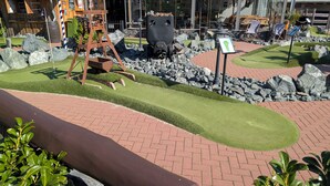 Ein Minigolfplatz mit künstlichem Rasen, Felsen und einer Holz-Schaukel.