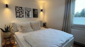 Ein modernes Schlafzimmer mit einem großen Bett, Wandbildern und einem Fenster mit Vorhängen.