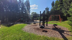 Ein Spielplatz mit Schaukeln, einer Rutsche und einer Kletterkonstruktion.