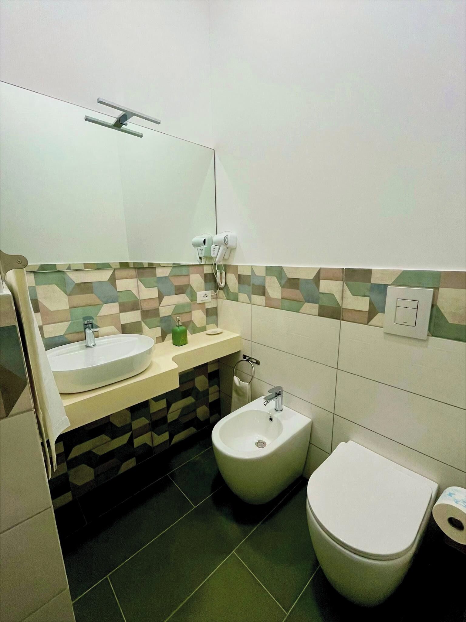 A bathroom with a sink, bidet, toilet, and a mirror.