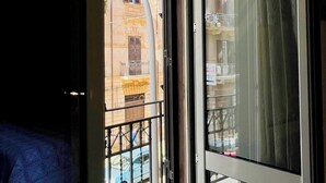 A view from a balcony with a building in the background, a window with a curtain, and a metal gate. - Le Suite Vintage Del Corso (Palermo)