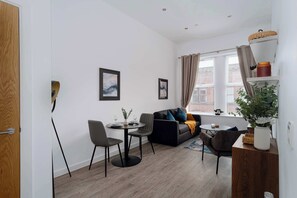 A modern living room with a sofa, chairs, a dining table, and artwork on the walls. - Spacious & Modern 1BED Apartment nr Etihad Stadium (Manchester)