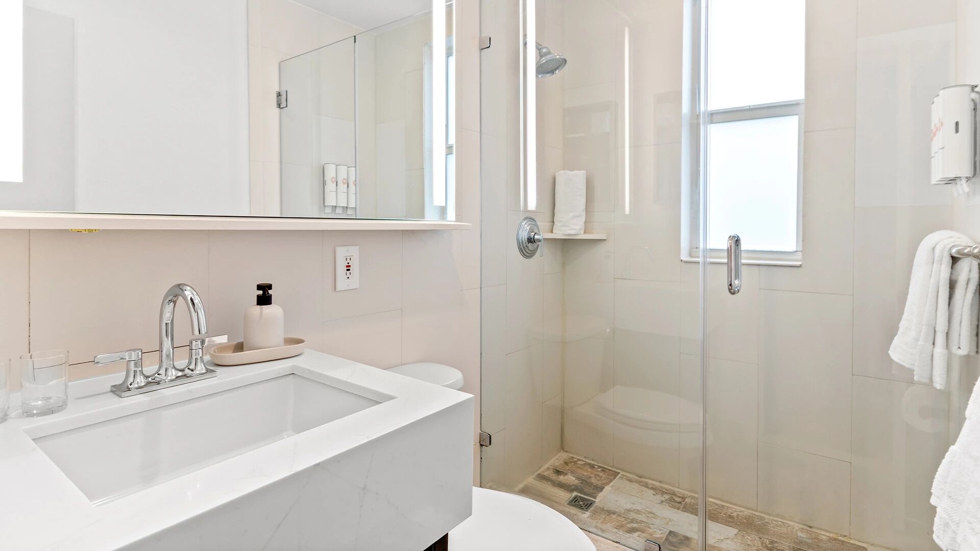 Een moderne badkamer met een grote spiegel, een wastafel, een douche en een toilet.