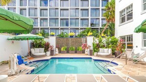A pool area with lounge chairs, a small pool, and potted plants.