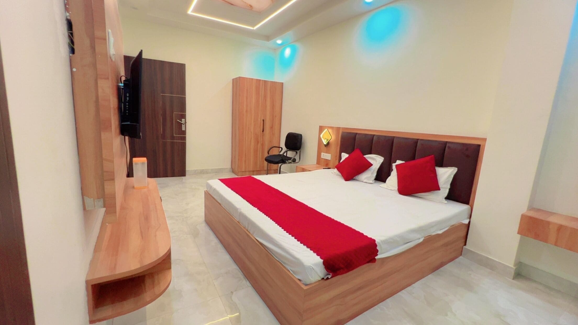 Une chambre d’hôtel moderne avec un grand lit, des meubles en bois, une télévision et une armoire.