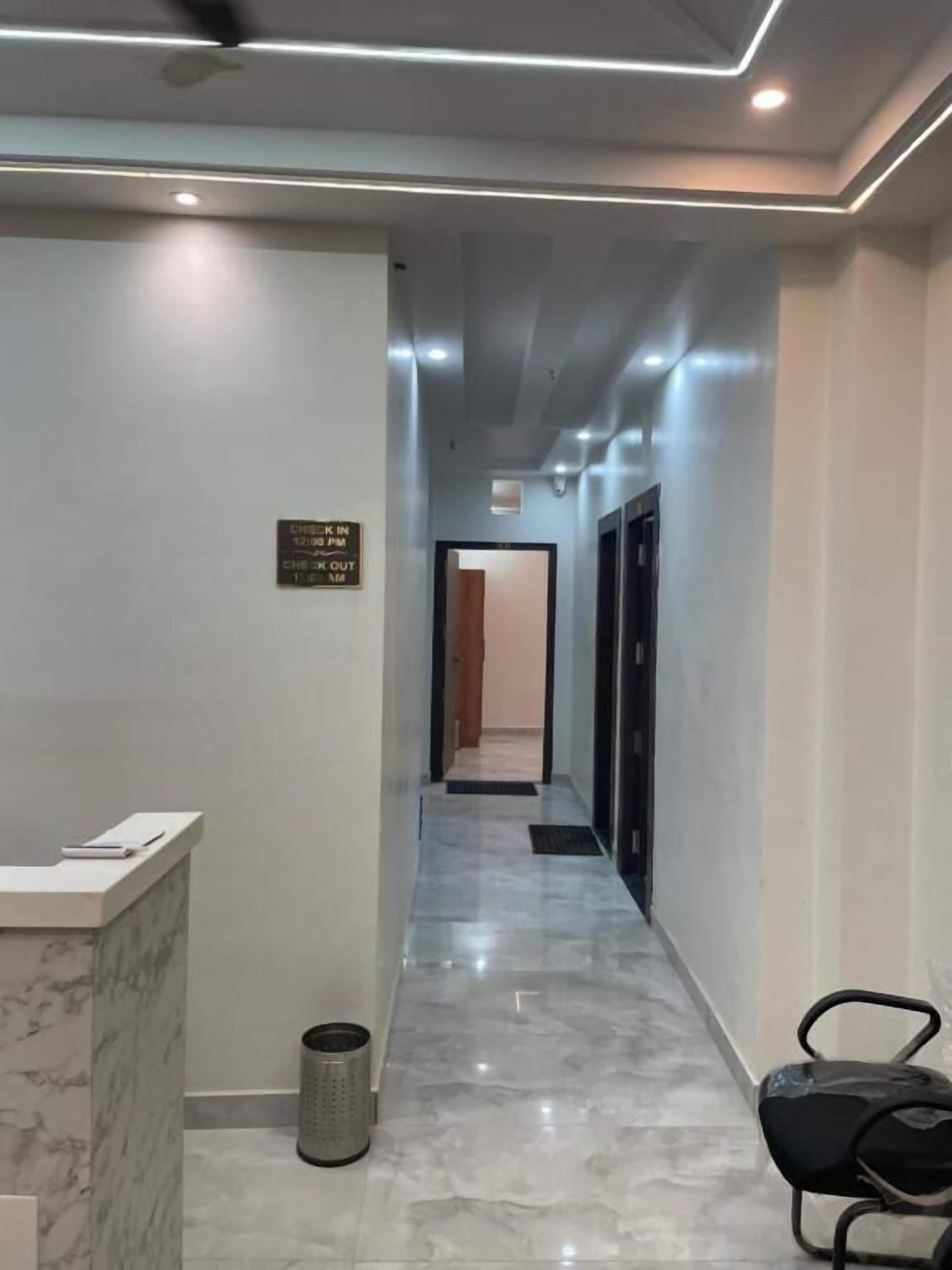 A hotel reception area with a marble floor, a reception desk, a trash can, and a seating area with chairs.