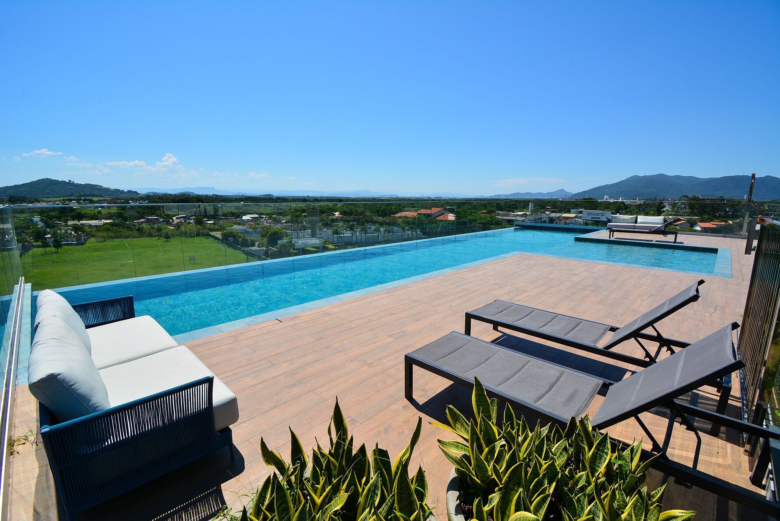 Área de piscina no terraço, com espreguiçadeiras e vista para a paisagem ao redor.