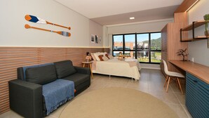 A modern room with a bed, a sofa, a desk, and a view of the outdoors. - Studio Shopping OKA Floripa - SOK211 (Florianópolis)