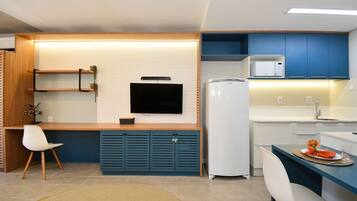 A compact kitchen with a flat-screen TV, a microwave, and a refrigerator.