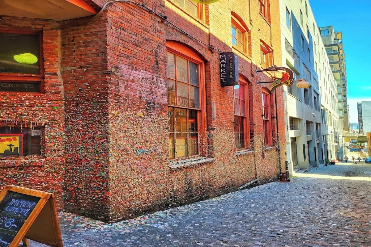 A brick building with a theater sign, cobblestone street, and a chalkboard signboard.