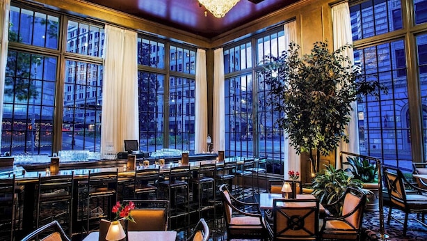 Un interior espacioso con ventanas amplias, una zona de bar y un candelabro.
