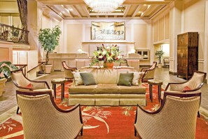 A spacious lobby with a sofa, armchairs, a coffee table, a large floral arrangement, and a staircase. - Classic Double Queen | Mayflower Park | Pike Place Steps, Family Base | 2 Units (Seattle)