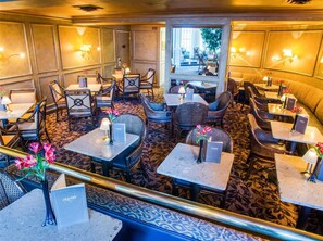 A restaurant with multiple tables and chairs, a patterned carpet, and wall-mounted lamps. - Classic Double Queen | Mayflower Park | Pike Place Steps, Family Base | 2 Units (Seattle)