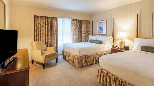 Une chambre d’hôtel avec un lit, une chaise, une télévision et une lampe.
