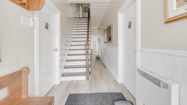 A hallway with a wooden bench, a staircase, and a radiator. - Auberge du vieux pont (Saint-Raymond)