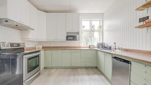 A kitchen with white cabinets, a microwave, a stove, and a dishwasher. - Auberge du vieux pont (Saint-Raymond)