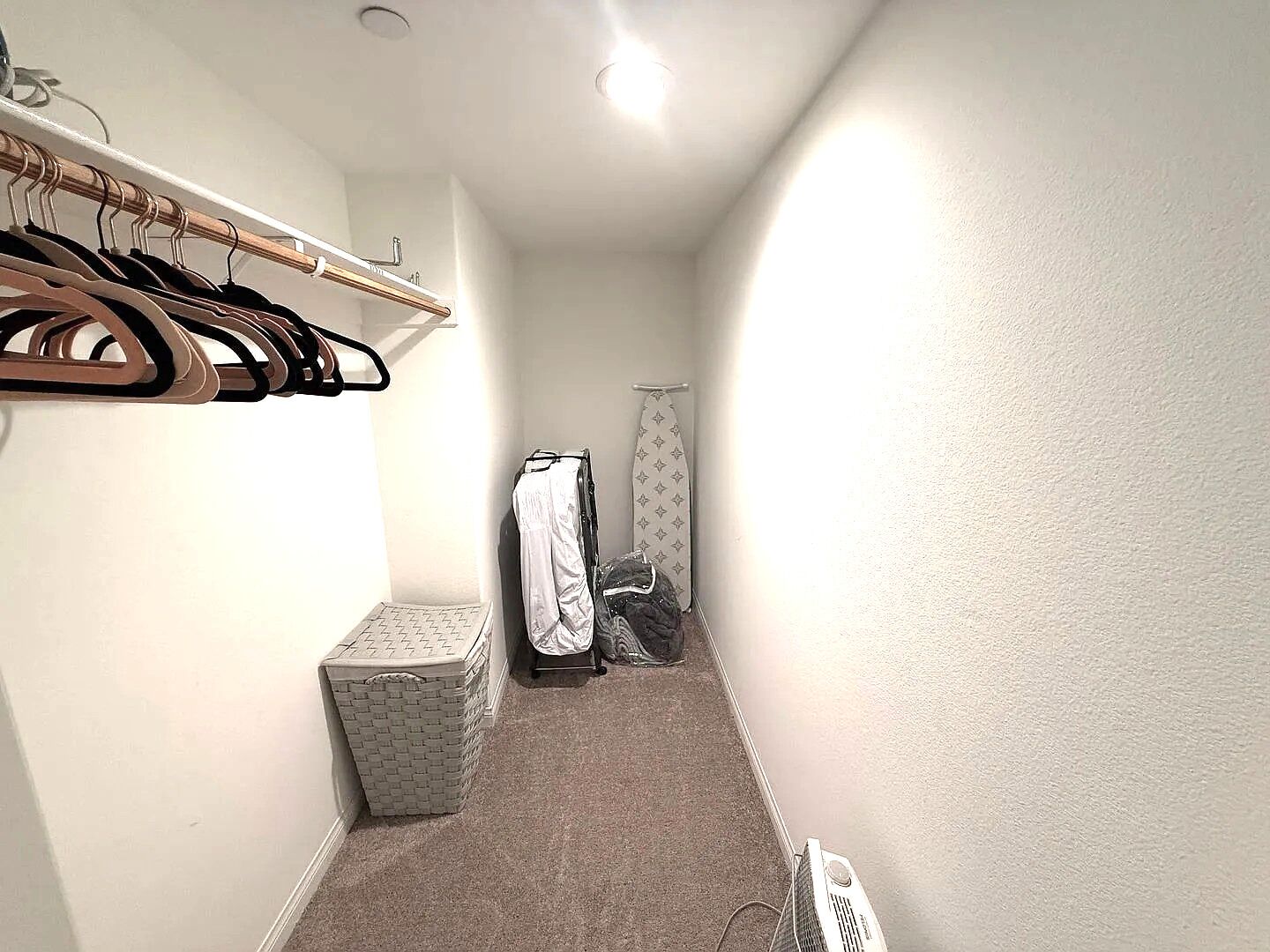 A narrow hallway with a clothing rack, a drying rack, and a laundry basket.