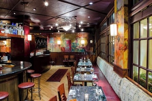 A restaurant with a bar area, tables with chairs, and a mural on the wall. - Queen City | Mayflower Park | Steps to Pike Place, Shop & Dine, City Break (Seattle)