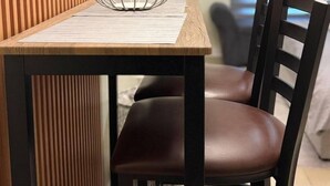 Una mesa para comer con un bol metálico, una silla de madera y un panel de pared de listones verticales.