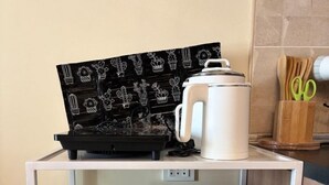 Una cocina con microondas, cafetera y una pizarra con dibujos de cactus.