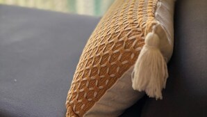 Una habitación con ventana, un sofá y un cojín decorativo.