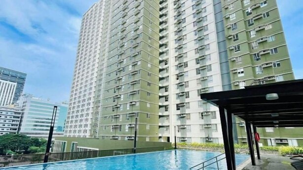 Un edificio residencial alto con piscina y zona cubierta.