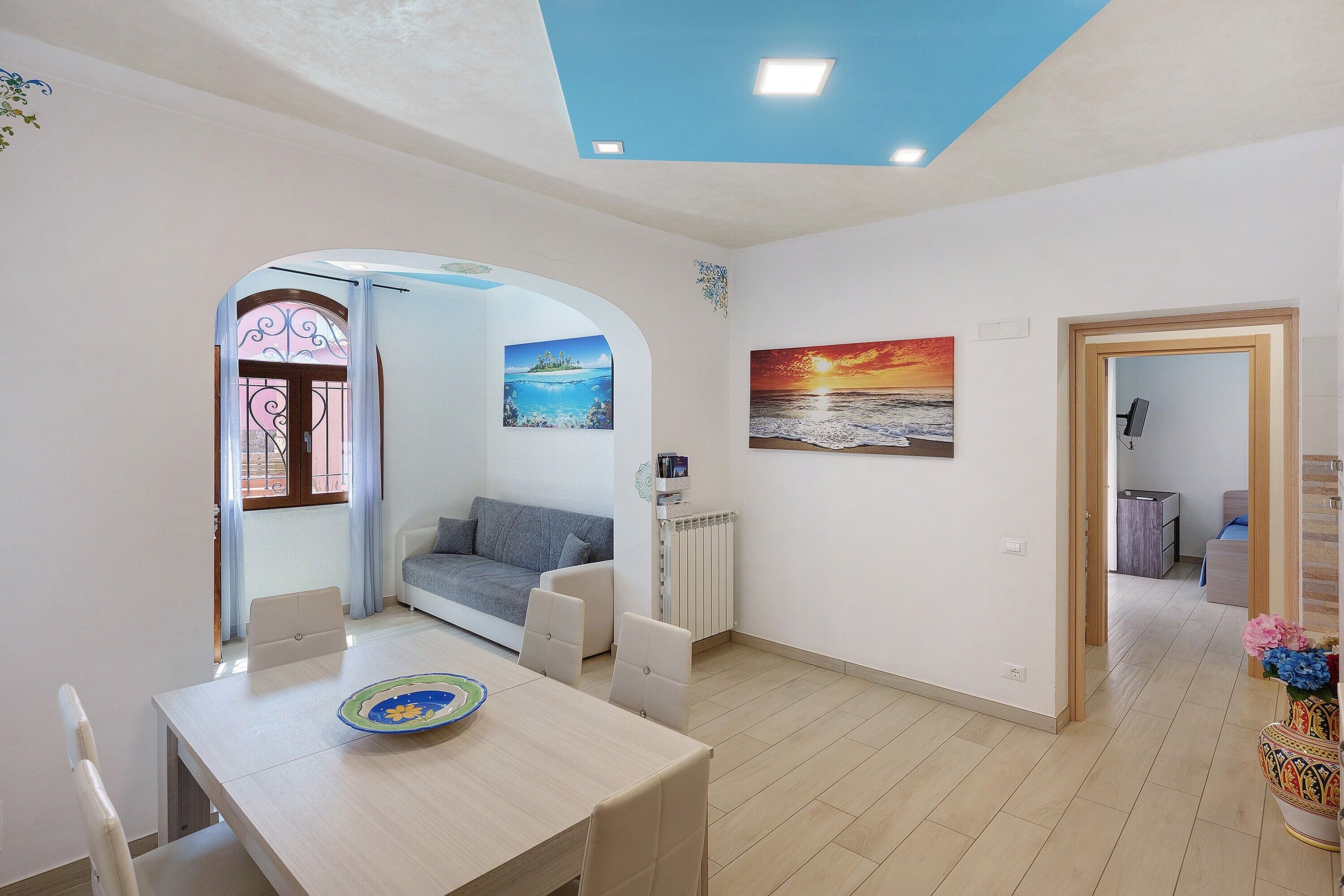A modern living room with a dining area, a sofa, a radiator, and a painting on the wall.