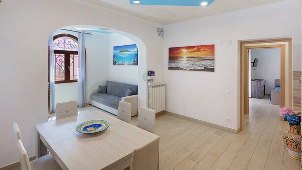 A modern living room with a dining area, a sofa, a radiator, and a painting on the wall. - Apartment 'Casa Mariateresa' with Mountain View, Wi-Fi, and Air Conditioning (Vico Equense)