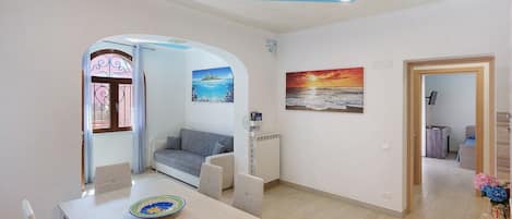 Una sala de estar moderna con comedor, sofá, radiador y un cuadro en la pared.