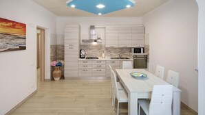 A compact kitchen with a dining area, a microwave, and a stove. - Apartment 'Casa Mariateresa' with Mountain View, Wi-Fi, and Air Conditioning (Vico Equense)