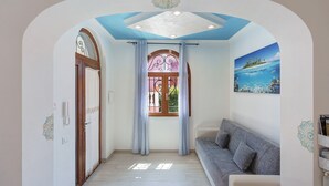 A hallway with a ceiling design, a window with curtains, a sofa, and a wall with a painting. - Apartment 'Casa Mariateresa' with Mountain View, Wi-Fi, and Air Conditioning (Vico Equense)