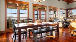 A spacious dining area with a large wooden table, multiple chairs, and a chandelier. - Family Retreat ~ Waterfront Luxury Home Sleeps 26 Comfortably (Centre)