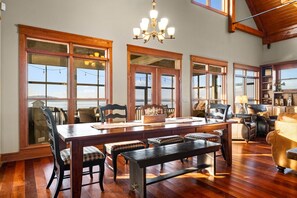 Un vaste espace dédié à la salle à manger, avec une grande table en bois, de nombreuses chaises et un lustre.