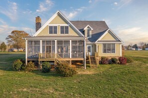 A two-story house with a covered porch, a chimney, and a well-maintained lawn. - Family Retreat ~ Waterfront Luxury Home Sleeps 26 Comfortably (Centre)