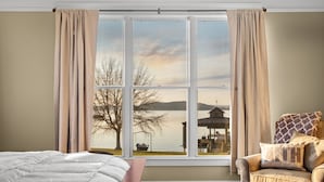 A room with a large window, a bed, a chair, and a view of a dock and lake. - Family Retreat ~ Waterfront Luxury Home Sleeps 26 Comfortably (Centre)